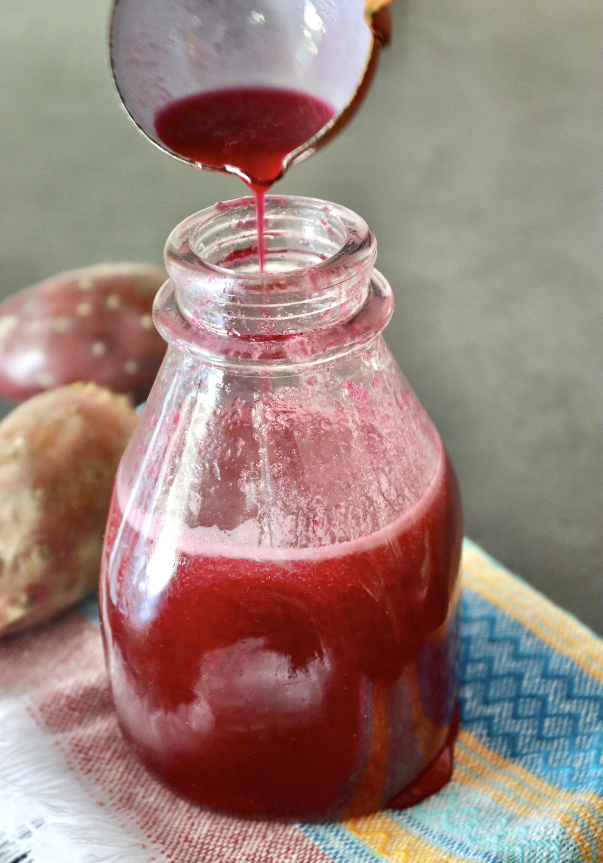 Prickly Pear syrup in a bottle with a small ladle adding more at the top.